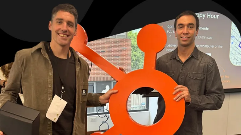 Dos integrantes del equipo de Wots sostienen el logotipo de HubSpot en el Summit LATAM 2025.